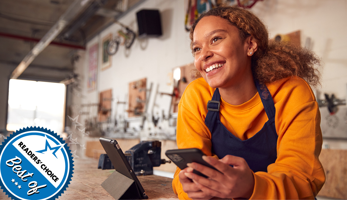 Smiling small business owner holding a phone.