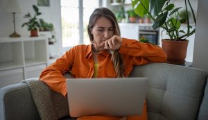 Woman searching on her laptop comfortably on her sofa.