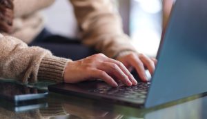 Close up of hands typing on a laptop keyboard.