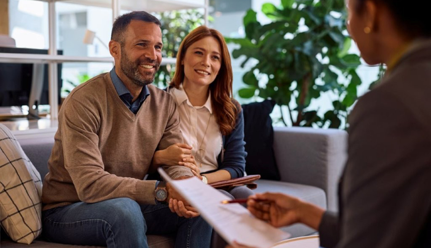 A couple smiling as they sit down with a financial planner.
